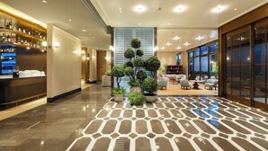 A hotel lobby with a polished marble floor, a reception desk, a seating area, and a large window. - Mercure Guangzhou Baiyun International Airport (Guangzhou)