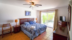 A bedroom with a bed, a nightstand, a chair, a ceiling fan, a TV, and a window with curtains. - Beautiful vacation home in Costa Blanca Golf & Villas by Decameron. (Rio Hato)