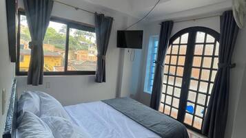 Une chambre à coucher avec un lit, une télévision et une fenêtre avec des rideaux.