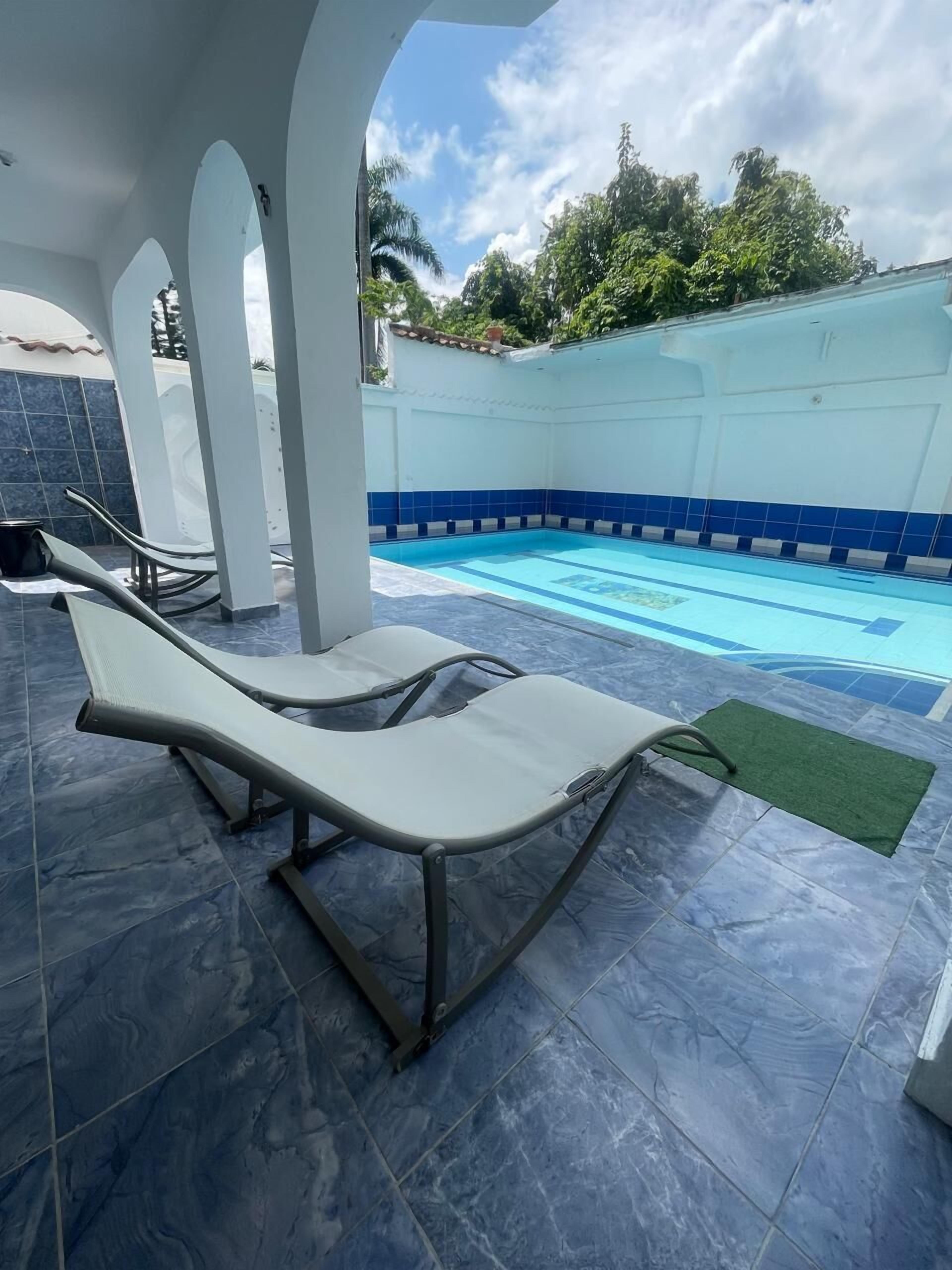 A swimming pool area with lounge chairs and a tiled floor.