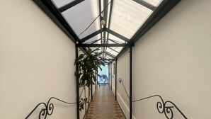 Ein Korridor mit einem gemusterten Boden, Metallgeländern und einer Glasdecke.
