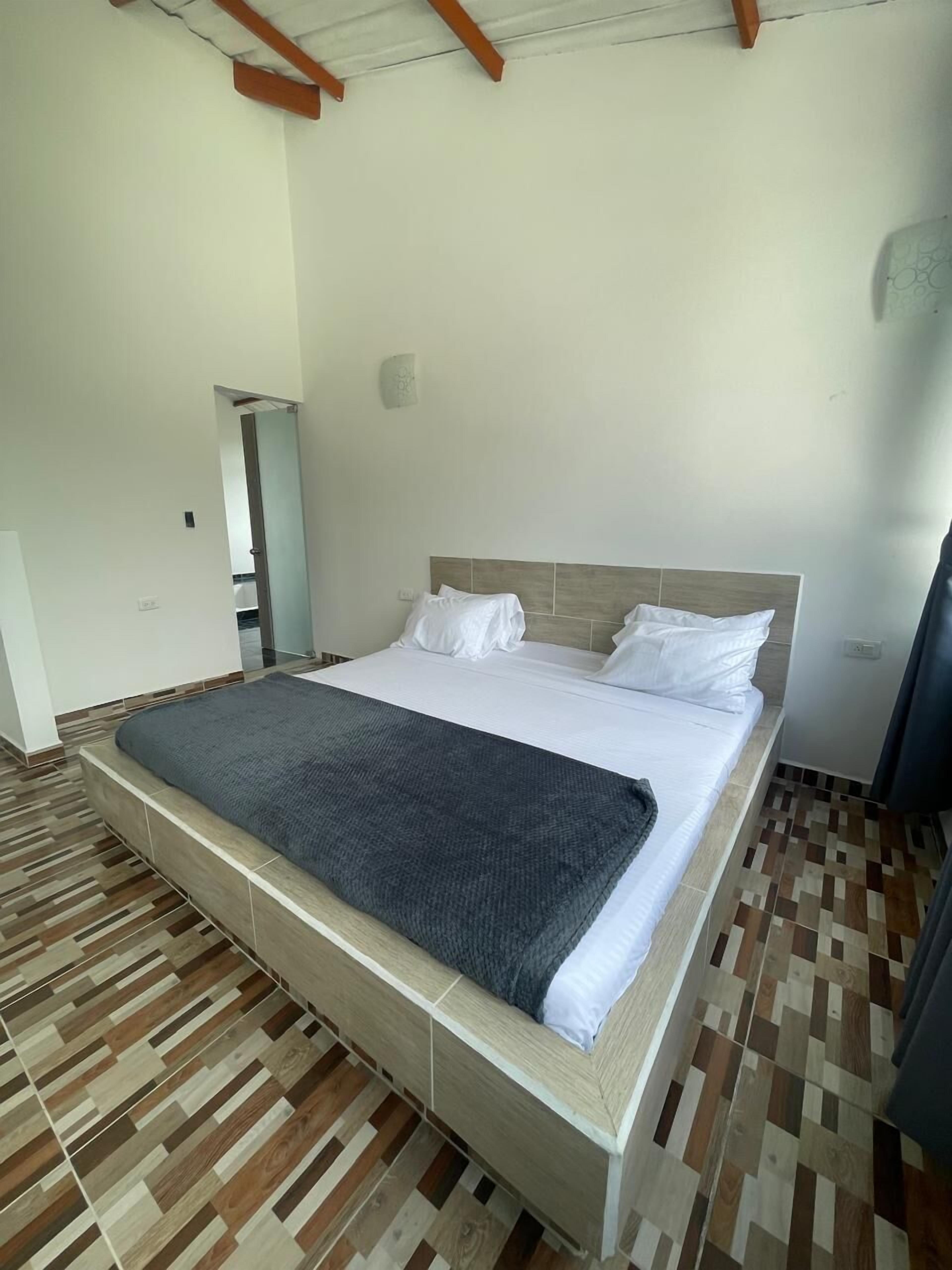A bedroom with a large bed, wooden floor, and a wooden ceiling beam.