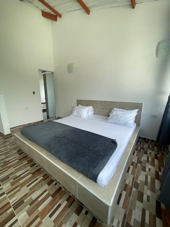 Un dormitorio con una cama grande, suelo de madera y una viga de techo de madera.