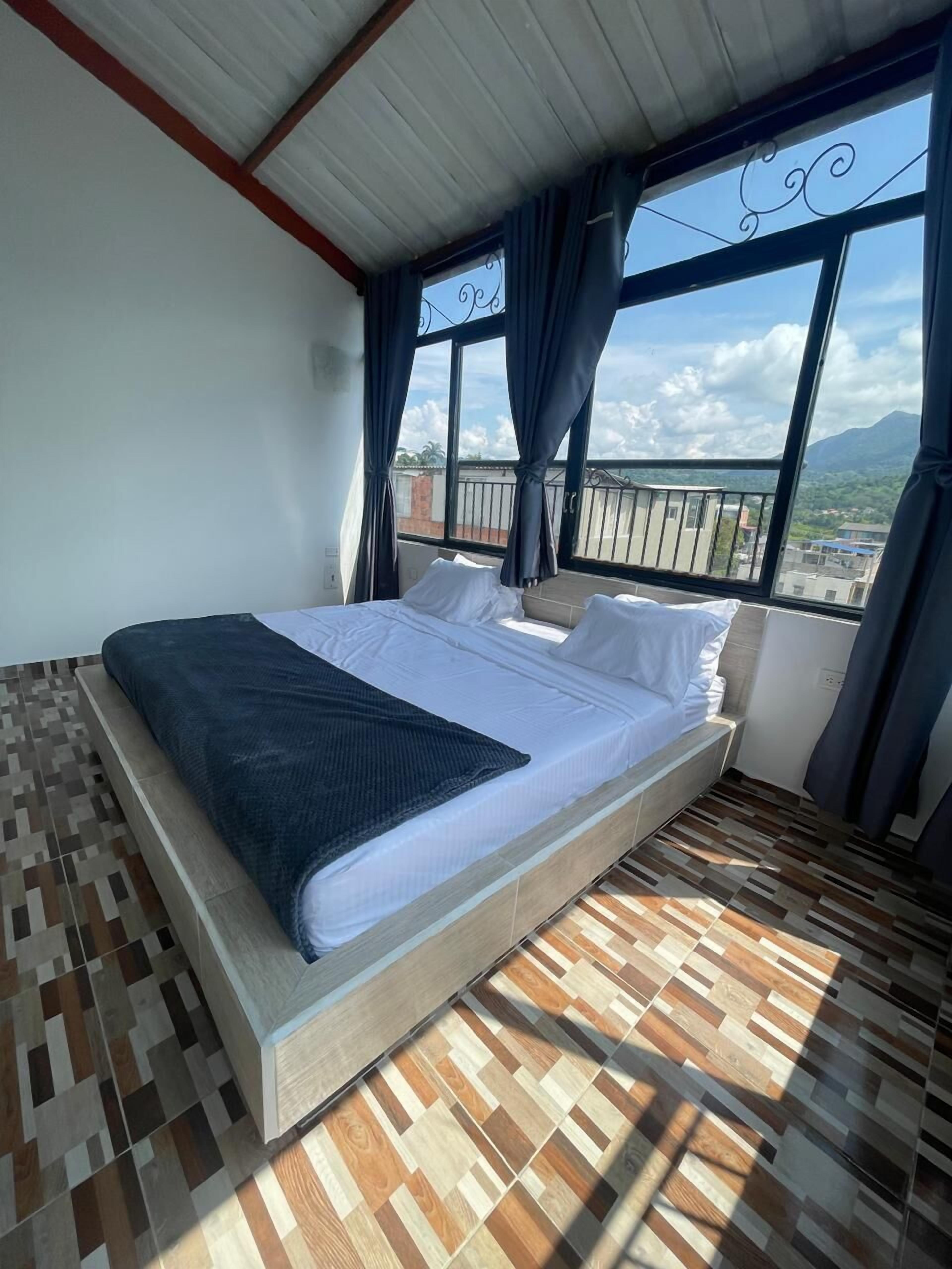 A single bed in a room with a view of a balcony and mountains.
