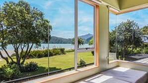 A room with a large window offering a view of a lake, greenery, and distant mountains.