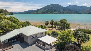 A two-story house with a flat roof, a covered patio, and a view of a large body of water and mountains in the background.