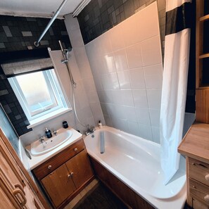 Huis | Badkamer | Een bad/douchecombinatie, een diep bad, een haardroger, handdoeken