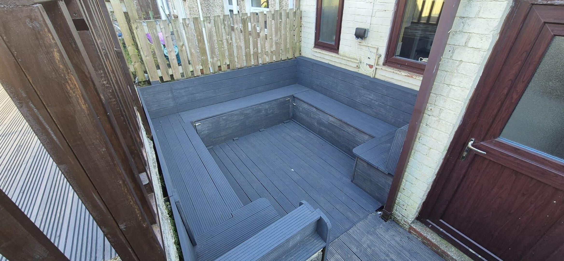A small, enclosed patio area with a wooden deck and a built-in bench.