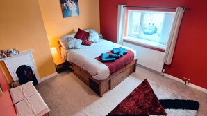 Una camera da letto con un letto, una finestra, un camino e un tappeto.