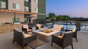 Una terraza en la azotea con asientos al aire libre, un brasero y vistas a una piscina.