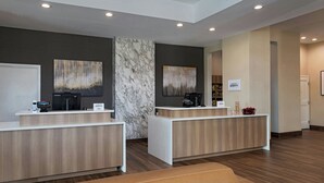 Un área de recepción con dos mostradores, una pared de mármol y suelo de madera.
