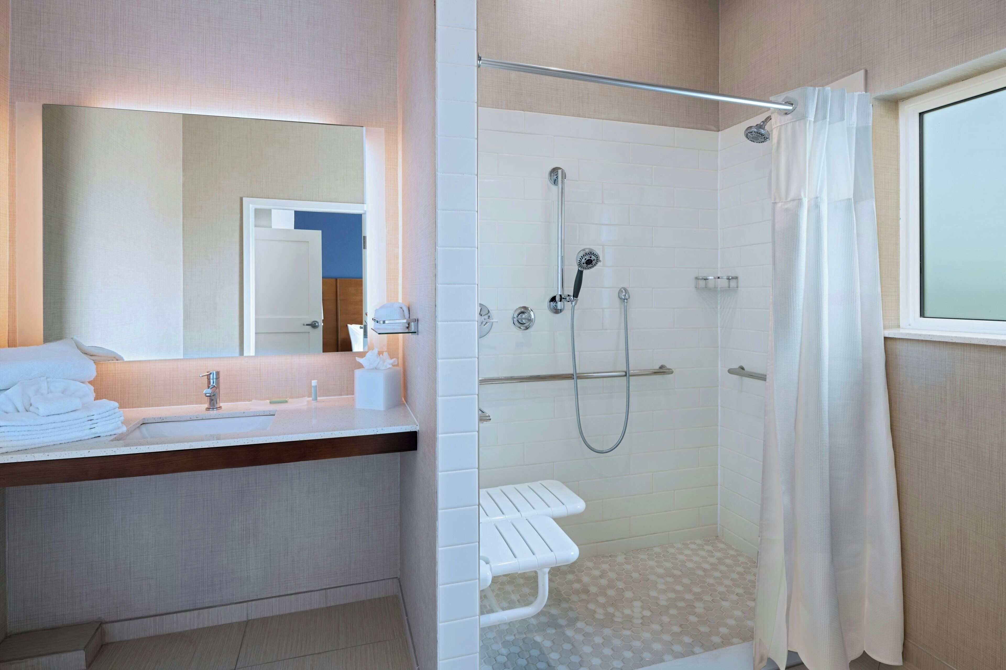 A modern bathroom with a glass-enclosed shower, a vanity with a mirror, and a towel rack.