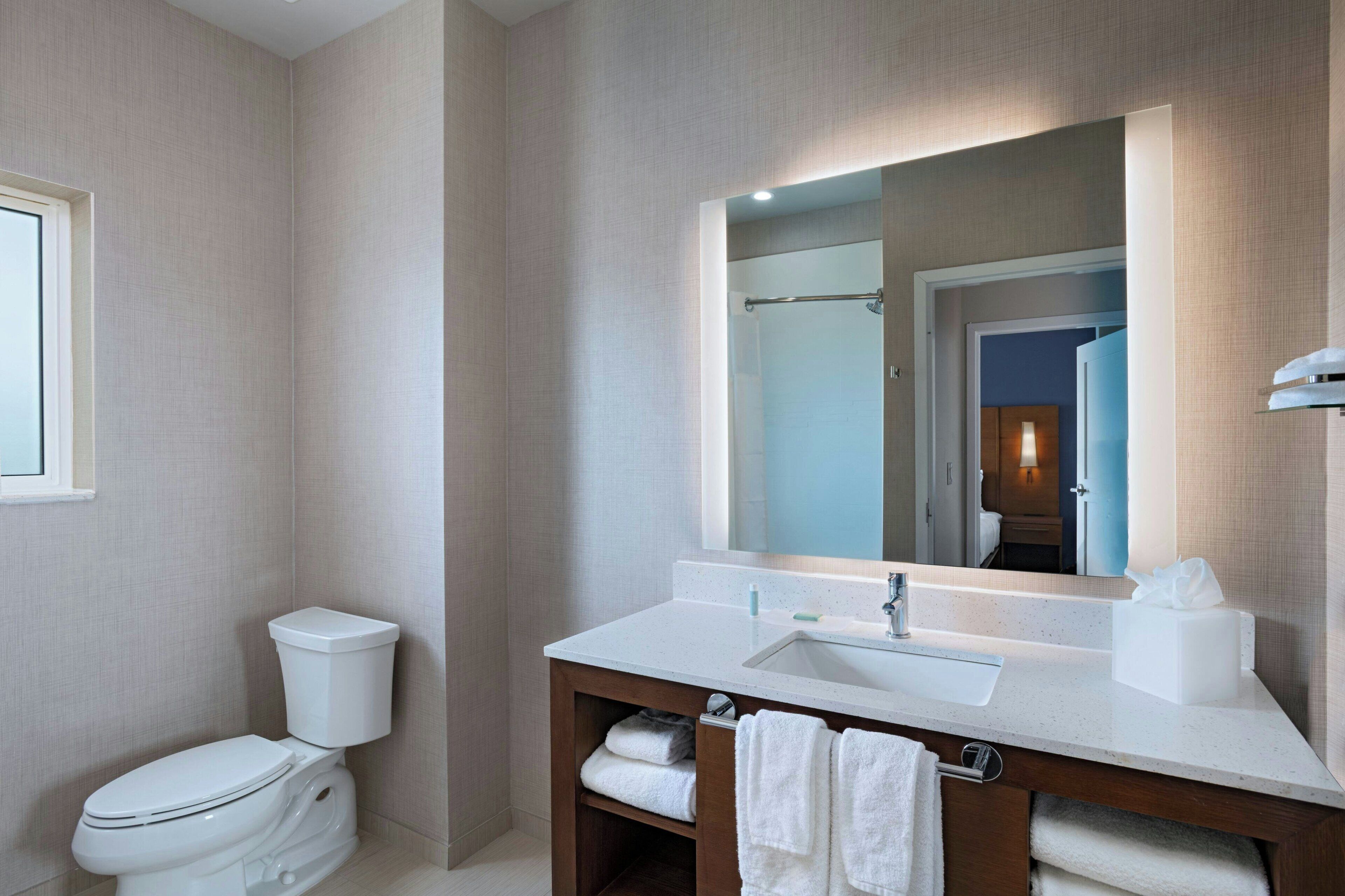 Une salle de bain moderne avec des toilettes, un lavabo et un miroir.