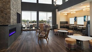 Amplio espacio interior con chimenea, varios conjuntos de asientos y grandes ventanales con vistas al exterior.