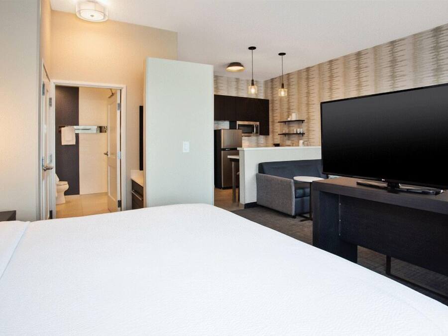 A hotel room with a bed, a TV, a kitchenette, and a bathroom.