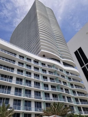 Um edifício moderno com fachada curva e várias varandas.