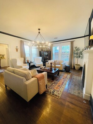 A living room with a sofa, armchairs, a coffee table, and a fireplace.