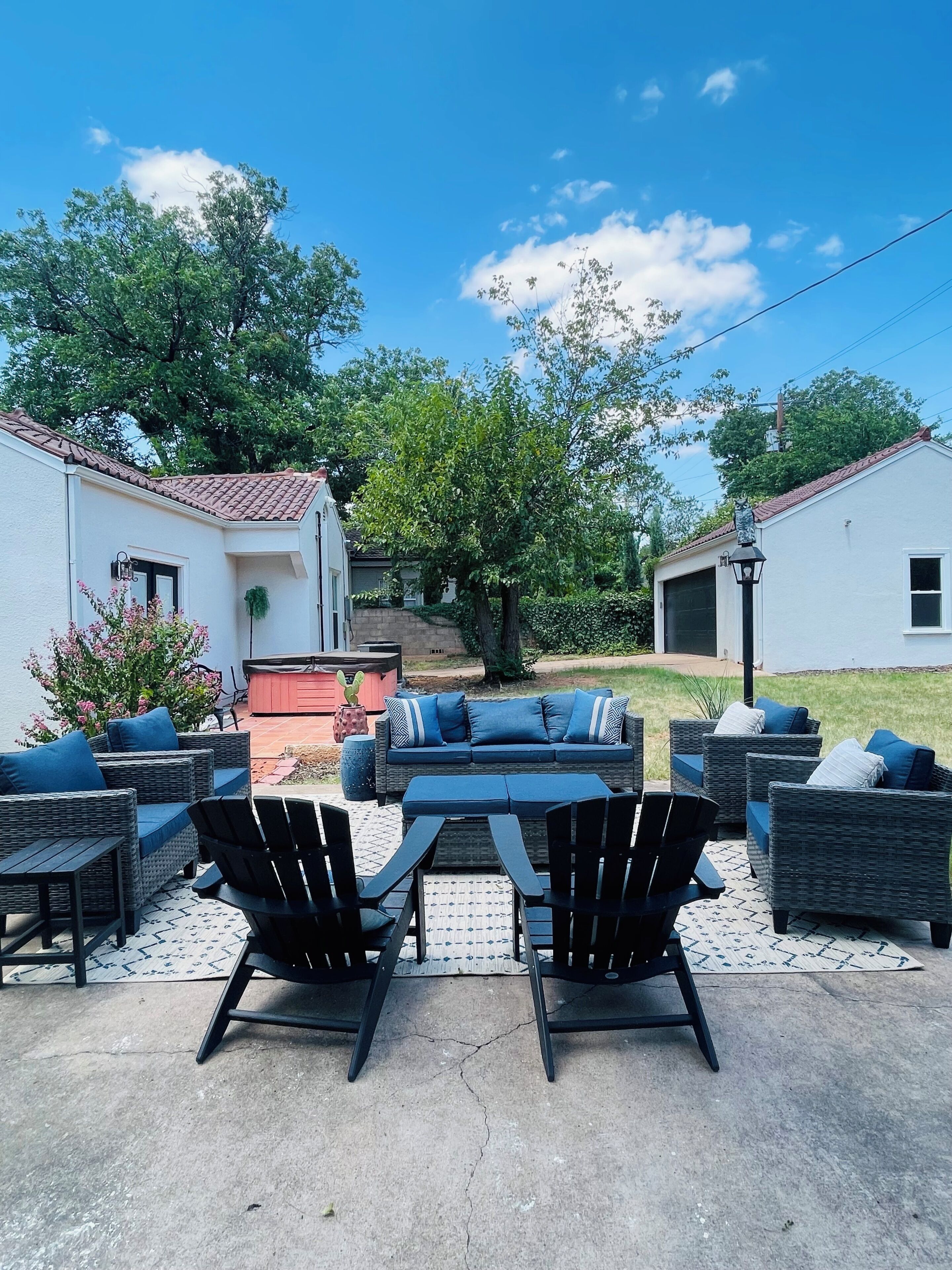 Un patio al aire libre con mobiliario de mimbre, una parrilla y vista a una zona residencial.