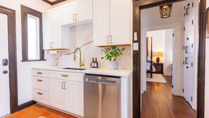 A kitchen with white cabinets, a stainless steel dishwasher, and a marble backsplash. - Old-World Charm in Abilene! Spanish Revival Home, Sleeps 8! (Abilene)