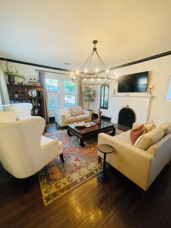 A living room with a fireplace, a television, and a chandelier.