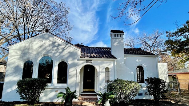 A white building with a tiled roof, a chimney, and a number '1025' sign. - Old-World Charm in Abilene! Spanish Revival Home, Sleeps 8! (Abilene)