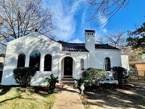 A white building with a tiled roof, a chimney, and a number '1025' sign. - Old-World Charm in Abilene! Spanish Revival Home, Sleeps 8! (Abilene)