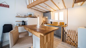 A modern kitchen with wooden beams, a central island, and a dining area with a chair.