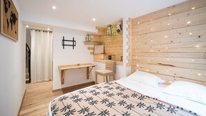 A bedroom with a bed, a desk, a chair, and a wooden headboard with lights.
