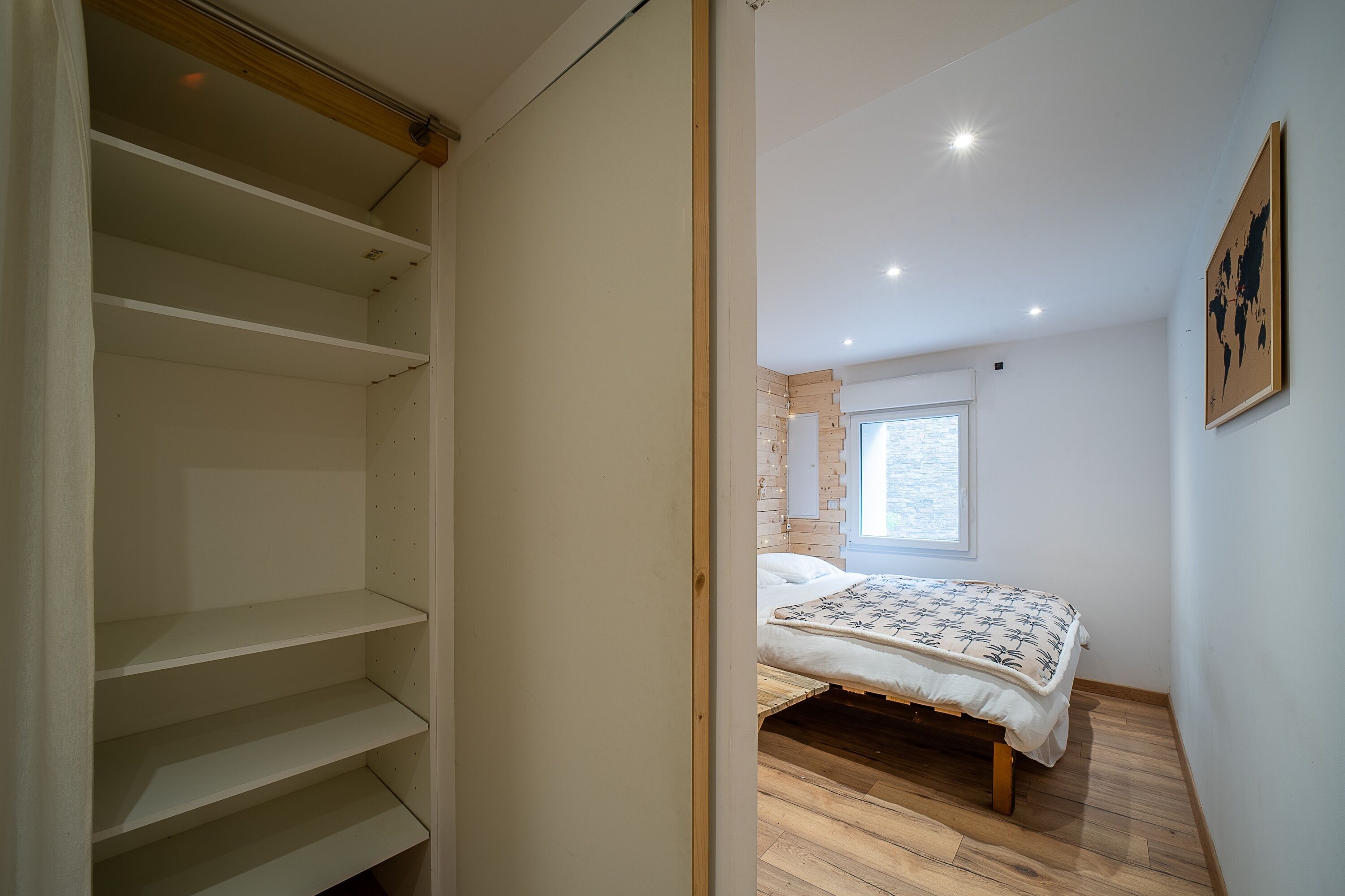 A bedroom with a bed, a window, and a wooden floor.