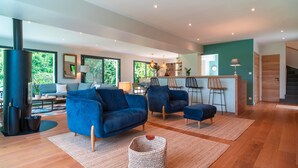 Ein modernes Wohnzimmer mit blauen Sofas, einer Küchenzeile und einer Treppe.