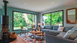Ein modernes Wohnzimmer mit Kamin, großen Fenstern, einer Couch und einem Couchtisch.