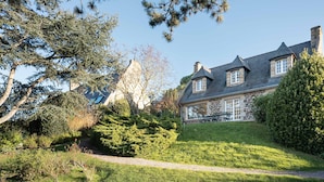 A stone house with a sloped roof, surrounded by a well-maintained garden and trees. - Ker Val - Belle maison avec jardin proche plage (Pléneuf-Val-André)