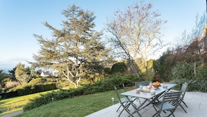 An outdoor patio with a table and chairs, surrounded by a well-maintained garden and trees. - Ker Val - Belle maison avec jardin proche plage (Pléneuf-Val-André)