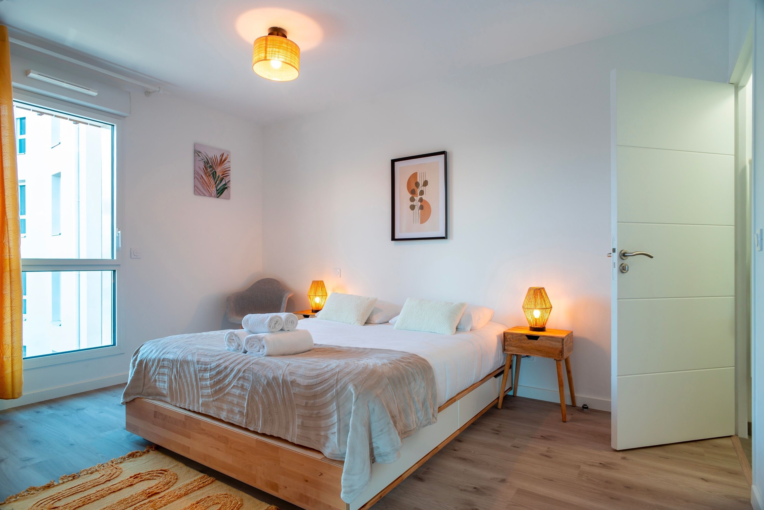 Une chambre à coucher avec un lit, des lampes de chevet, une porte et une fenêtre.