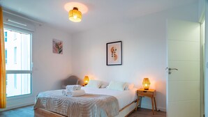 A bedroom with a bed, bedside lamps, a door, and a window.