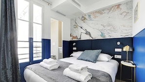 A modern hotel room with a large bed, a marble-patterned wall, and a view through a window with curtains. - Serene cocoon for 2P with AC - Near Montmartre (Paris)