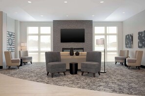A modern lobby with a large flat-screen TV, comfortable seating, and a fireplace.