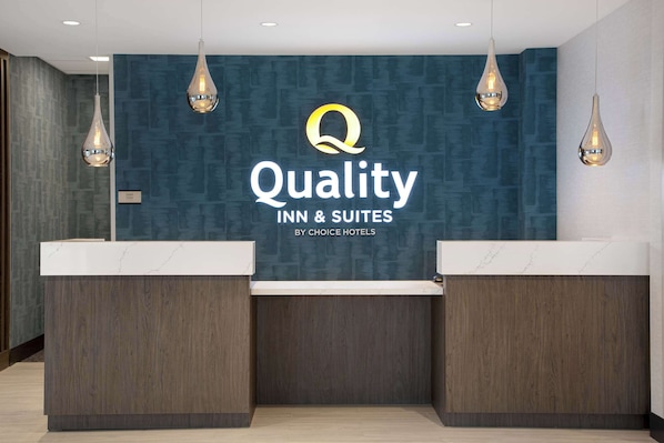 A reception desk with a blue textured wall, a logo, and three pendant lights.