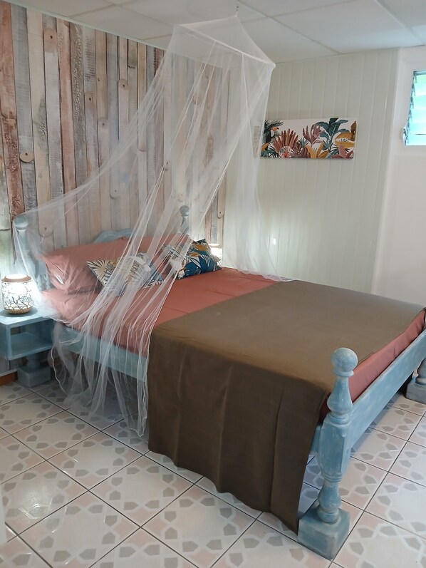 Een bed met hemelbed, een nachtkastje, een muur met een houten paneelontwerp en een schilderij.