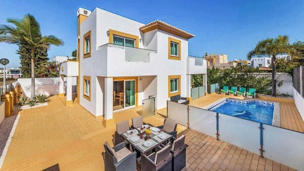 Ett modernt hus i två våningar med en uteplats, en swimmingpool och en matplats.