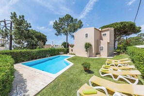 Une piscine, des chaises longues et un bâtiment doté d’un toit plat.