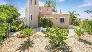 Una casa a due piani con un giardino, un vialetto in pietra e un piccolo stagno.