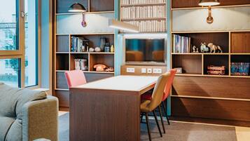 Eine moderne Bibliothek mit Bücherregalen, einem Tisch, Stühlen und einem Fernseher.