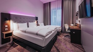 Een moderne hotelkamer met een groot bed, een bureau, een stoel, een televisie en een raam met gordijnen.