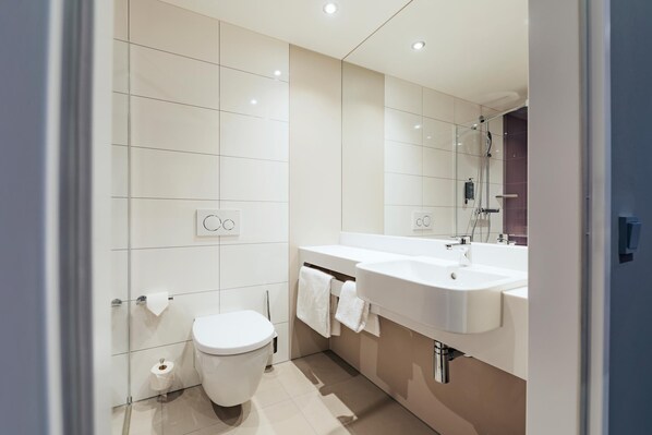 A modern bathroom with a toilet, sink, and shower.