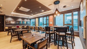 Een modern restaurant met verschillende eetgedeeltes, grote ramen en diverse zitmogelijkheden.