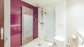 A modern bathroom with a glass shower enclosure, a white toilet, and a marble-tiled floor.