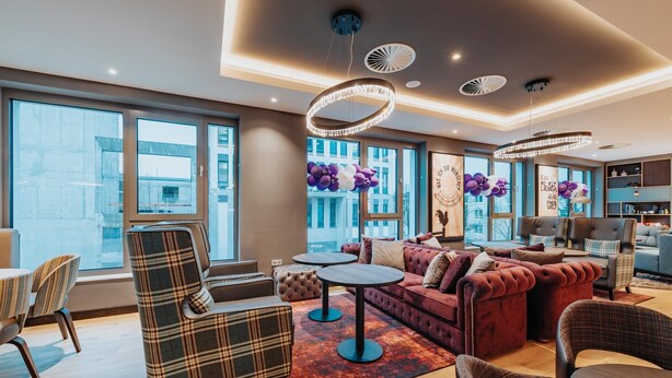 Een moderne woonkamer met een bank, fauteuils, een salontafel en een eethoek met stoelen en een tafel.