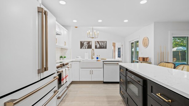 A modern kitchen with white cabinetry, a marble countertop, and a central island.