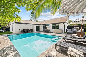 A modern house with a swimming pool, outdoor seating, and a TV screen. - Casita Delray Oasis: 4BR with Pool, Hot Tub, BBQ, Firepit, Pool Table (Delray Beach)